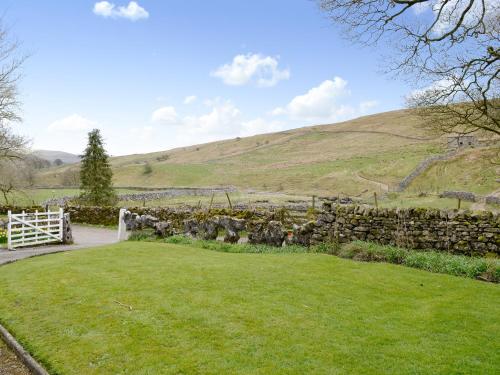 a garden with a stone wall and green grass at East House Farm in Beckermonds