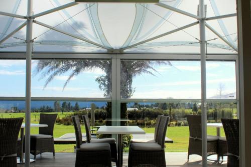 einen Wintergarten mit Tischen und Stühlen und einem großen Glasfenster in der Unterkunft Franz Josef Oasis in Franz Josef