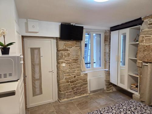 - une cuisine avec un mur en pierre et un four micro-ondes dans l'établissement Calm and central apartment, à Quimper