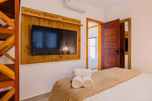 a bedroom with a bed with a tv on the wall at Apê Rustic Chic na Rua do Mucugê - Café da manhã opcional - Estilo e Localização Premium in Porto Seguro