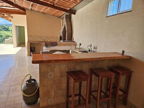 a kitchen with a counter with stools and a sink at Chácara Nonna Rosa in Socorro