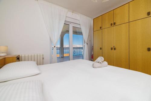 a bedroom with a large white bed and a balcony at Apartments Marija in Senj