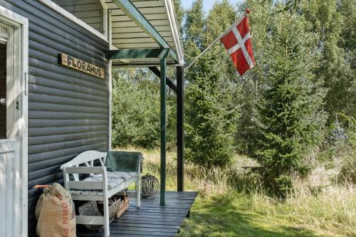 a flag on the porch of a house with a chair at Wooden House With Wild Garden By Sejerø Bay in Kalundborg