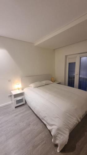 een witte slaapkamer met een groot bed en een nachtkastje bij Braga 2 Bedrooms Nice Flat in Braga