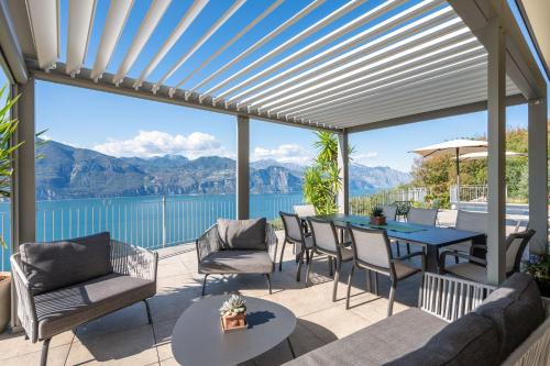 a patio with a table and chairs and a view of the water at Alleinstehende Villa Mit Pool Und Traumaussicht in Castelletto di Brenzone