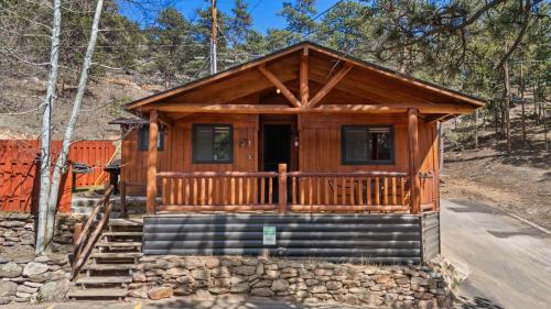 a cabin in the woods with a porch and stairs at Cabin 1- Hot Tub Grill- Mins to RMNP in Estes Park