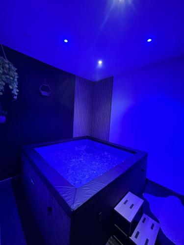 a blue room with a tub with a blue light at La cachette de Georgette in Landrecies