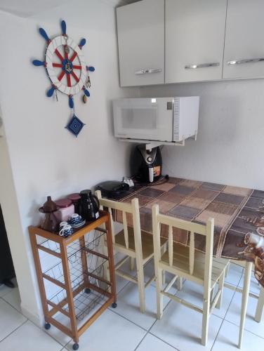 a kitchen with a table and chairs and a clock on the wall at Espaço inteiro-Praia de Barequeçaba - São Sebastião -SP in São Sebastião
