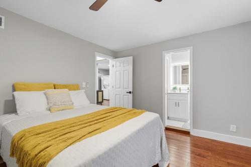 a white bedroom with a large bed with a yellow blanket at Little Indale Haus - Near Downtown and Prince Ave in Athens