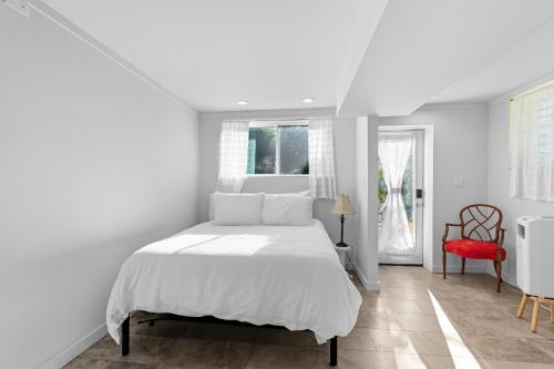 a white bedroom with a white bed and a red chair at The Briarcliff Suite in Athens