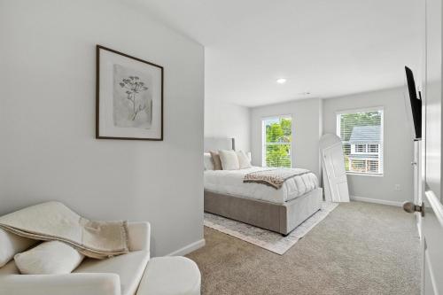 ein weißes Schlafzimmer mit einem Bett und einer Couch in der Unterkunft New Listing The Neutral Nook with Firepit in Athens