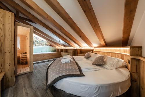 Cama grande en habitación con paredes de madera en Suite Illuminata con piccolo centro wellness, en Commezzadura