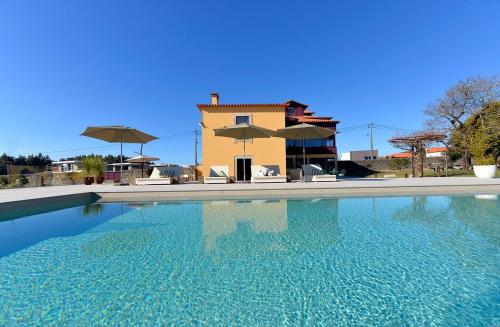 ein Pool vor einem Haus mit Sonnenschirmen in der Unterkunft Ferienhaus für 12 Personen in Esposende, Regio Norte Parque Natural do Litoral Norte in Esposende