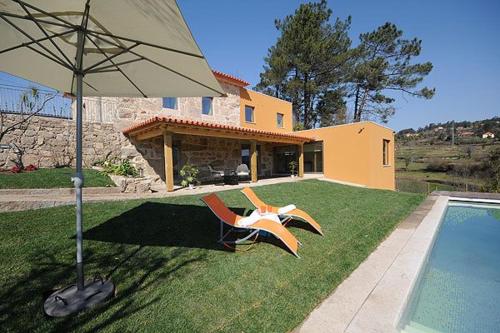 ein Haus mit einem Garten mit Pool und Sonnenschirm in der Unterkunft Ferienhaus für 10 Personen in Cossourado, Regio Norte Minho in Linhares