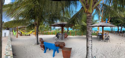 einen Strand mit Tischen, Stühlen und Palmen in der Unterkunft Fonte dos Corais - Suíte Lua na Praia in Maragogi