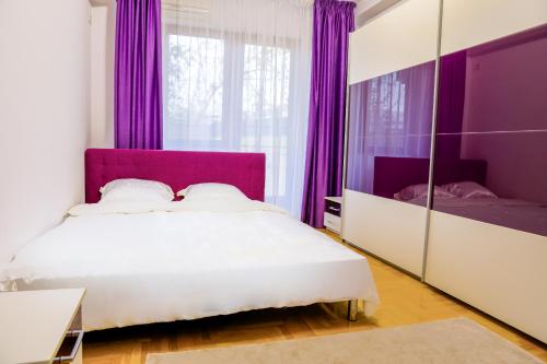 1 dormitorio con 1 cama con cortinas moradas y espejo en Elegant Central Stay - Targul de Craciun Craiova, en Craiova