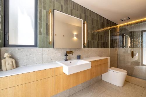a bathroom with a sink and a toilet and a mirror at Birdsong Sanctuary - Be My Guest Waiheke in Waiheke Island
