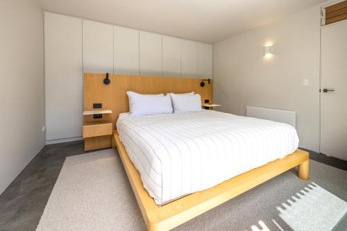 a bedroom with a large bed with a wooden frame at Birdsong Sanctuary - Be My Guest Waiheke in Waiheke Island