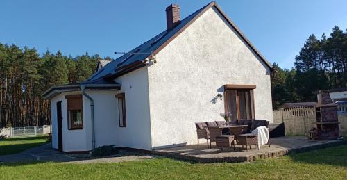 ein kleines weißes Haus mit einem Tisch und Stühlen in der Unterkunft Leśny Domek in Piłka