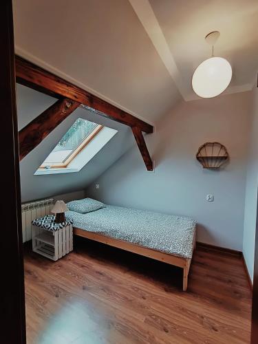 a attic room with a bed and a window at Leśny Domek in Piłka