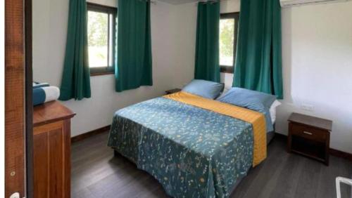 a small bedroom with a bed with green curtains at HUAHINE- Fare Montagne in Parea