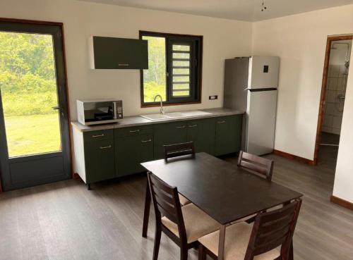 a kitchen with a table and a refrigerator at HUAHINE- Fare la Mer in Parea