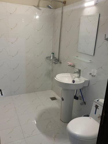 a white bathroom with a toilet and a sink at Amberwood residency in Islamabad