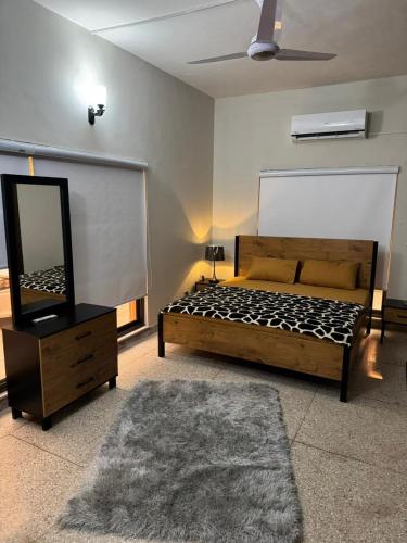 a bedroom with a bed and a dresser with a mirror at Amberwood residency in Islamabad