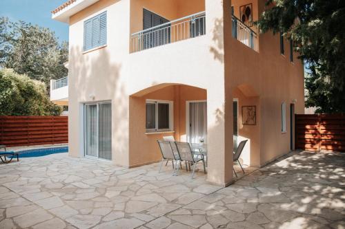 a patio with a table and chairs in front of a house at Villa Aphrodite in Paradise Gardens - 3bd with Private Pool by VICHY Holidays in Nea Paphos
