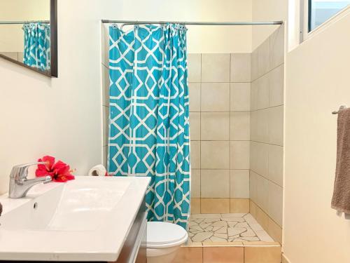 a bathroom with a blue shower curtain and a toilet at Studio with a view of a heavenly lagoon in Bora Bora