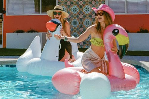two women are sitting on inflatables in a swimming pool at The Muse Hotel in Palm Springs