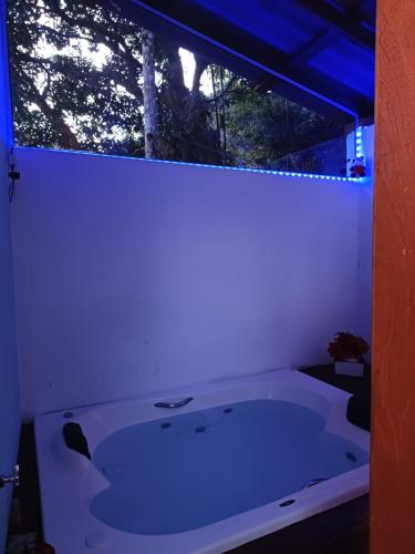 a white bath tub in a room with a window at Chalé com jacuzzi Florianópolis in Florianópolis