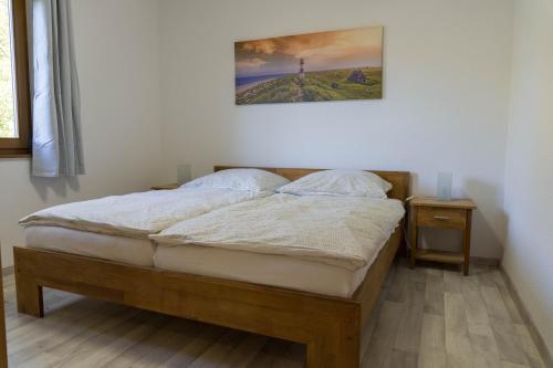 ein Bett in einem Schlafzimmer mit einem Bild an der Wand in der Unterkunft Haus Aurora Lodge in Frielendorf