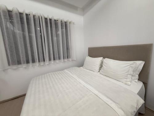 a bedroom with a bed with white sheets and pillows at Ani Apartment with Fireplace in Tirana