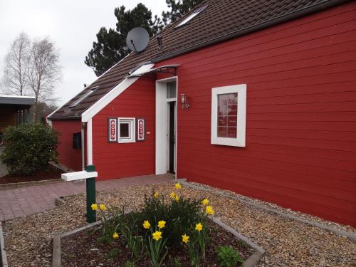 a red building with yellow flowers in front of it at Ferienhaus Achtein in Westoverledingen