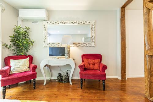 a living room with two red chairs and a mirror at Lisbon Core Apartments Bairro Alto in Lisbon