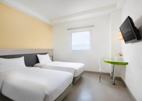 a hotel room with two beds and a table at Amaris Hotel Pettarani - Makassar in Makassar
