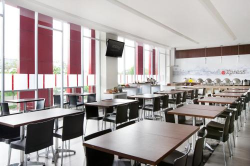 a dining room with tables and chairs and windows at Amaris Hotel Pettarani - Makassar in Makassar