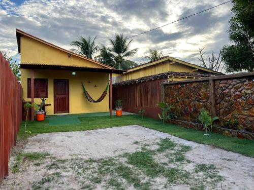 a yellow house with a fence and a yard at Refúgio Marajoara in Soure