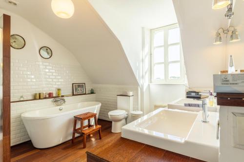 ein Badezimmer mit einer weißen Badewanne und einem WC in der Unterkunft Château de Penfrat in Gouesnach