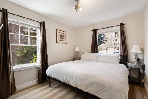 une chambre avec un grand lit et deux fenêtres dans l'établissement Drake Cottage 311, à Bend