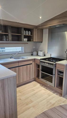 a kitchen with wooden cabinets and a stove top oven at Sunrise Holidays Skegness - Pearl in Skegness
