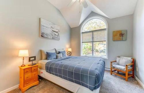 a bedroom with a bed and a window and a chair at Lake and Ski Escape with Hot Tub Coming Soon in Lake Harmony