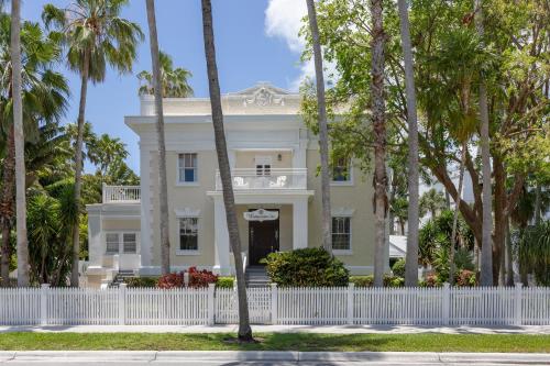 a white fence in front of a house with palm trees at Weatherstation Inn Circa 1911 in Key West