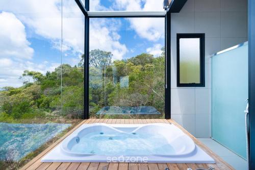 Una bañera en un baño con una ventana grande. en Cabaña con chimenea e hidromasaje! VST044, en Annitapolis