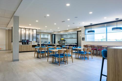 a restaurant with blue tables and chairs and a cafeteria at Home2 Suites By Hilton Kalamazoo Southeast in Kalamazoo