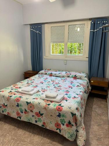 una camera da letto con un letto con un piumone floreale e due finestre di Hotel Abetaia a Villa Gesell