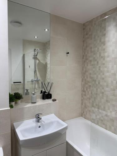 a bathroom with a sink and a tub and a mirror at Modern Refurbished Apt in Stevenage Town Centre in Stevenage