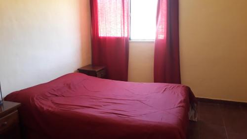 een slaapkamer met een bed en een raam met rode gordijnen bij Rancho Laramie in Huerta Grande