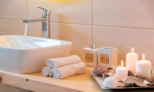 La salle de bains est pourvue d'un lavabo et de bougies sur un comptoir. dans l'établissement Orientem Villa Beheizter Pool, à Georgioúpoli